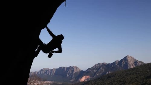 rock climber climbs a difficult route on a rock in the form of an arch