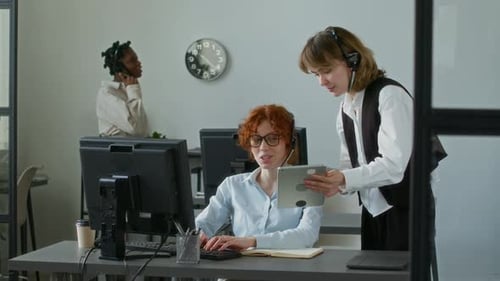 Young Woman Coming up to Female Coworker with Digital Tablet and Asking for Help