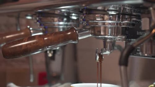 Espresso Dripping From Coffee Machine Through Portafilter Into Cup. close up