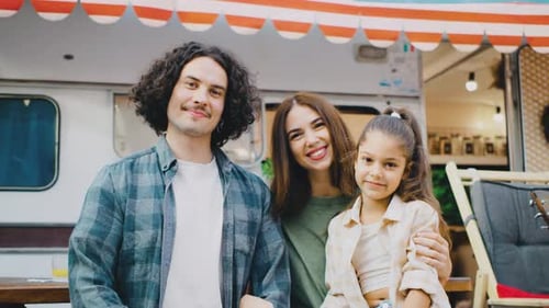 Smiling Family Posing in Front of Camping Van