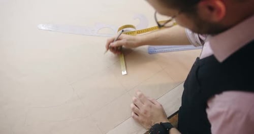 Male Successful Fashion Designer Draws a New Sketch Measures with a Ruler the Parameters of the