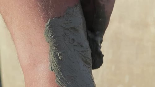 Putting mud on a leg. Medical and healing mud from the spa.