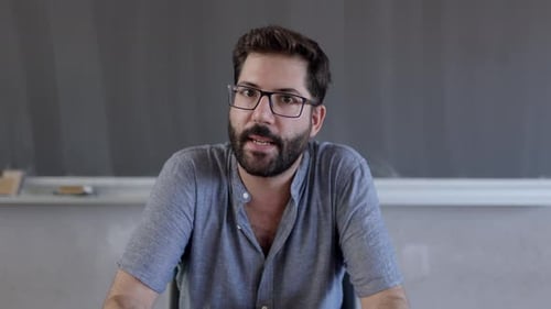 Man Talking in Front of Blackboard