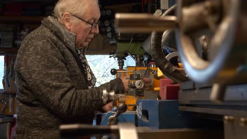 Mature man mechanical engineer setting up a lathe in workshop.