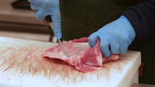 Butcher Cutting Raw Meat with Knife Close Up