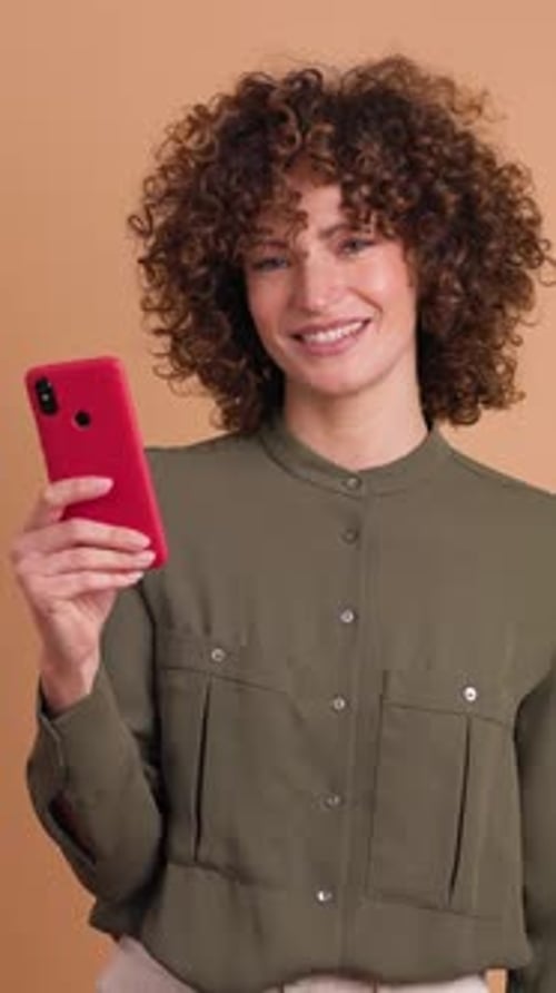Happy Woman Using Cellphone Pointing in Beige Studio Vertical Orientation