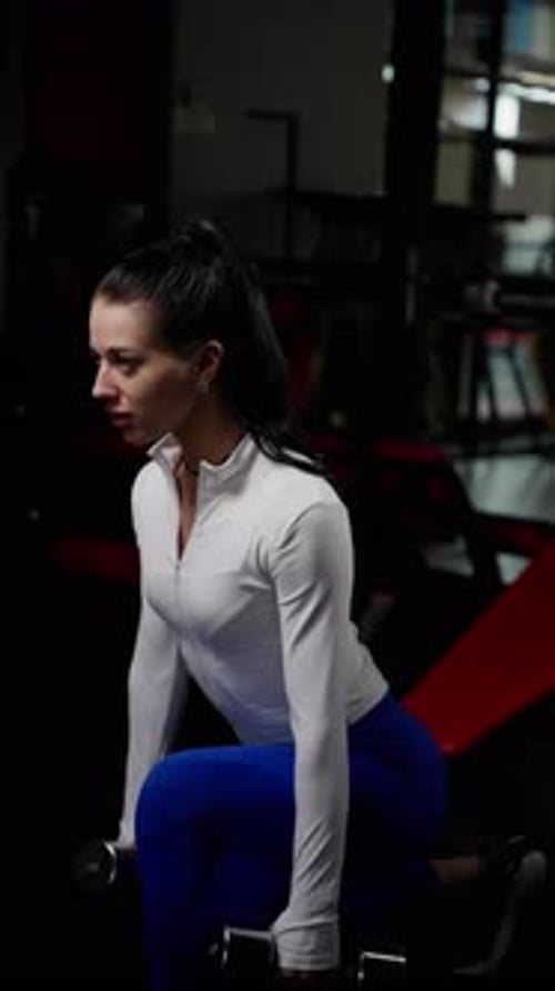 A Woman is Lifting Weights in a Gym