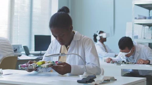 Group of Student Engineers Examining Circuit Boards in Lab