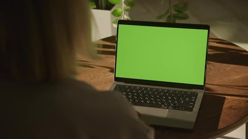 Handheld Shot of an Unrecognisable Caucasian Woman Watching a Laptop Computer with Green Screen