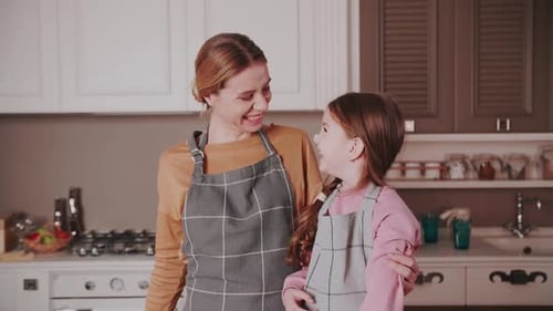 Loving Mother and Daughter in Kitchen Wearing Aprons