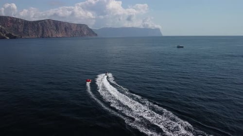 Jet Ski Tows Tube on Ocean in Coastal View