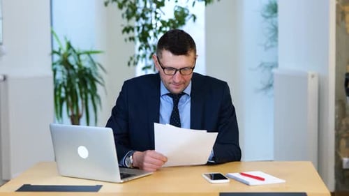 Excited Businessman Reads Good News at Desk