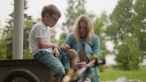 Mother Cleans Son's Bleeding Leg After Bicycle Accident