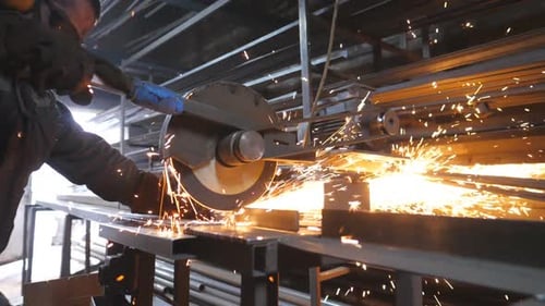 Industrial Worker with Circular Saw Sawing Steel in Workshop