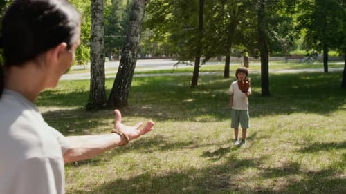 Man Teaching his Son to Catch Basketball Ball in Park