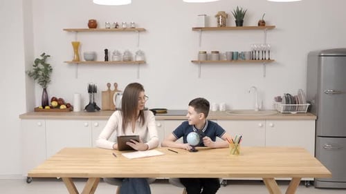 Woman and Boy Studying at Kitchen Table