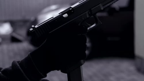 Schwarz-Weiß-Video Hände eines Mannes in Handschuhen mit einer Waffe oder Pistole beim Nachladen eines Banditenkriminellen