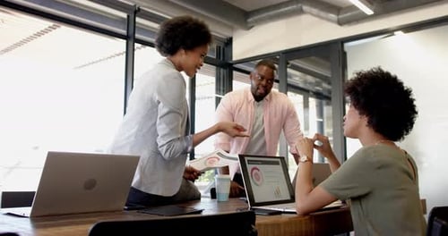 Business colleagues brainstorming, discussing charts and graphs in modern office