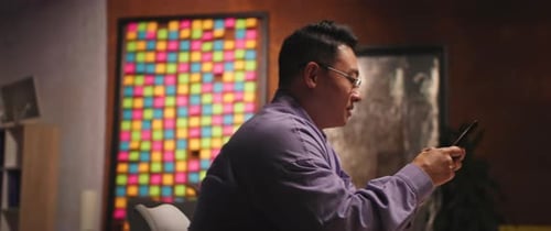 Man sits using mobile phone in modern home