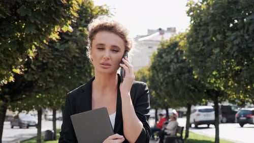 Serious Businesswoman Walking Outdoors in City Woman Talking Mobile Phone Call