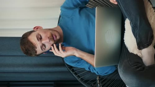 Young Adult Talking on Mobile Phone with Laptop