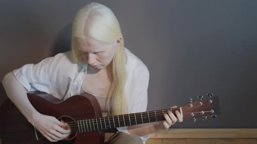 Woman Playing Acoustic Guitar in an Indoor Setting