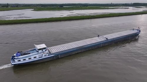 Cargo Ship Cruising On River In Alblasserdam, Netherlands. ascending drone shot, tilt-down