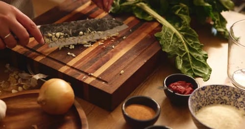Hands chopping garlic on a cutting board