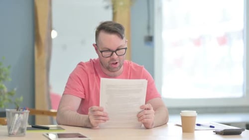 Man Reads Document and Celebrates Success at Office