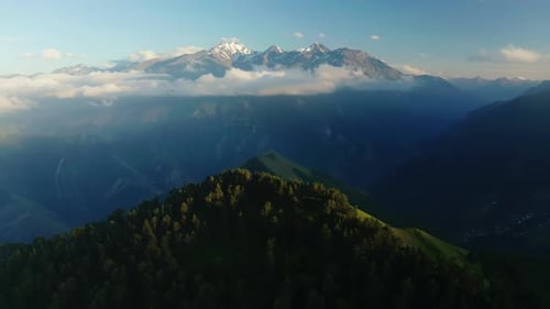 First Light of Day Illuminates Snowy Peaks Above the Forest Sunrise Over Misty Mountains with