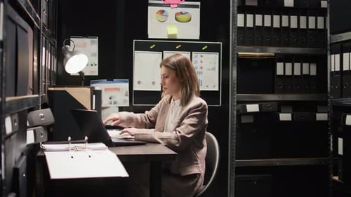 Woman Working in Small Dark Office Typing on Laptop