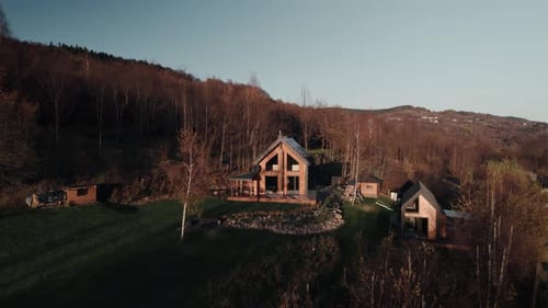 Aerial footage of wooden cabin house in forest at sunset light