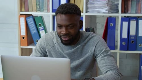 Portrait d'un directeur ambitieux et joyeux appréciant sa profession en travaillant au bureau afro-américain