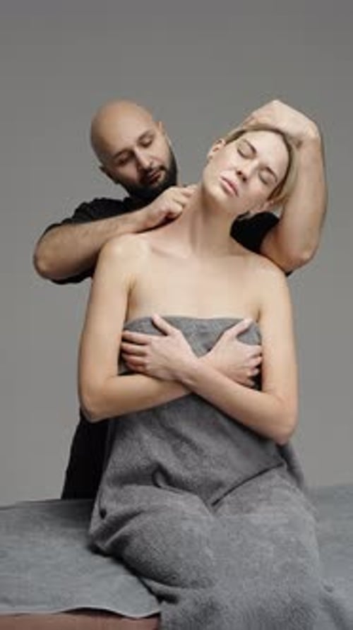 Therapist Performs Targeted Neck and Shoulder Massage on a Seated Client Wrapped in a Towel
