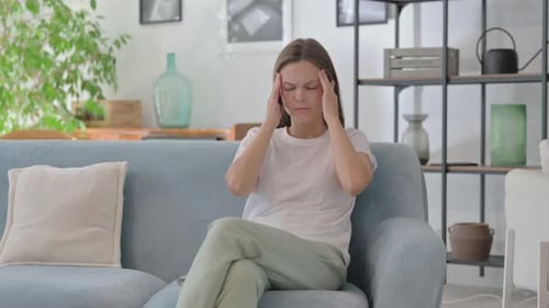 Young Woman with Headache Sitting on Sofa at Home