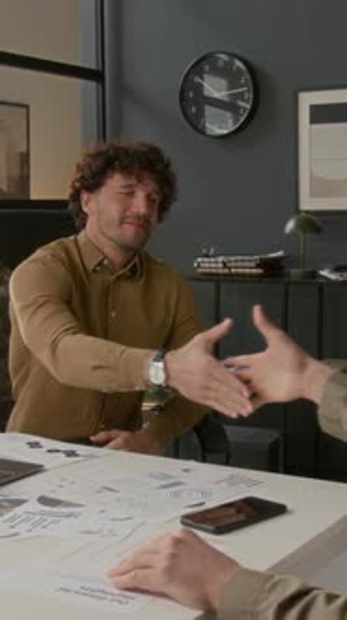 Smiling Young Male Company Head Shaking Hands with Unknown Employee in Office