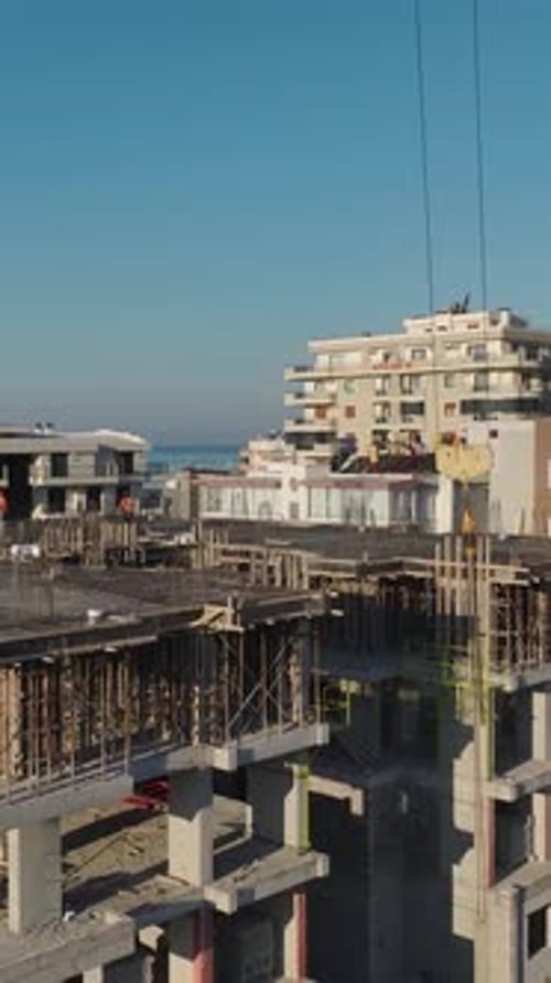 Vertical Video of Residential Construction With Workers Installing Structural Beams and a Crane