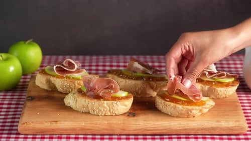 Tapas espagnoles, une femme place une tranche de jambon serrano sur un pintxo, fond de table à carreaux