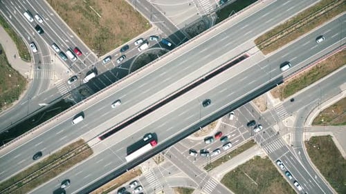 Overhead drone shot of traffic driving over roundabout with highway tunnel underneath, infrastructur