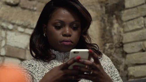 Negra, una mujer afroamericana con un teléfono móvil. Foto manual casual.