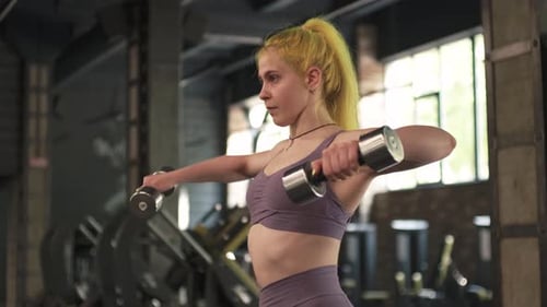 Gorgeous Female Professional Bodybuilder Doing Workout Exercises in Gym