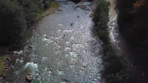 Four Sportsmans in Blue Inflatable Canoes are Rafting Down a Mountain River