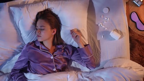 Woman Sleeps in Bed with Medicine Nearby