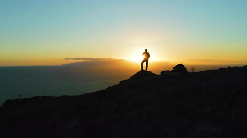 Silhouette of Man on Mountain Top at Sunset