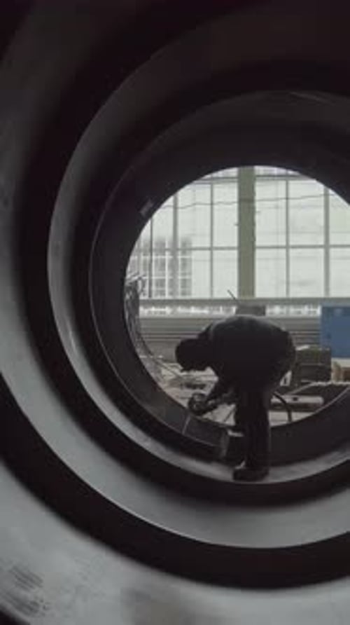 Ein Industriearbeiter wird in einem großen Rohr in einer geschäftigen Fabrikumgebung gesehen, einem Lagerbestand