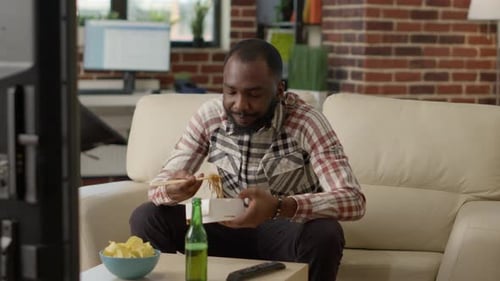 Man Eats Takeout on Couch at Home
