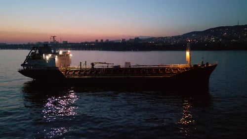 Aerial View of Industrial Tanker Ship at Sea During Sunset with City Lights