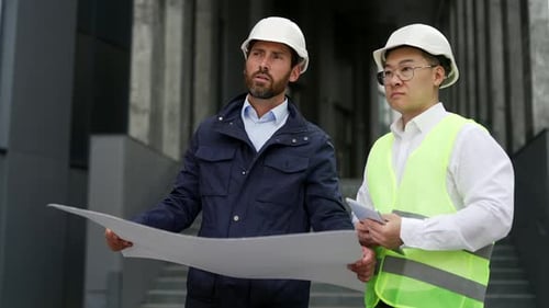 Construction Engineers Reviewing Blueprint Outside Building