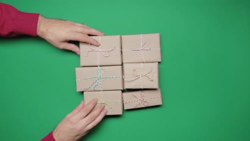 Man Gives His Woman Bunch of Craft Paper Wrapped Gift Boxes on Green Background