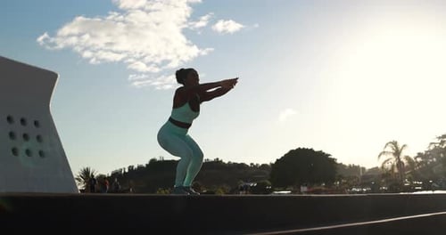 Woman in activewear doing squats at sunrise